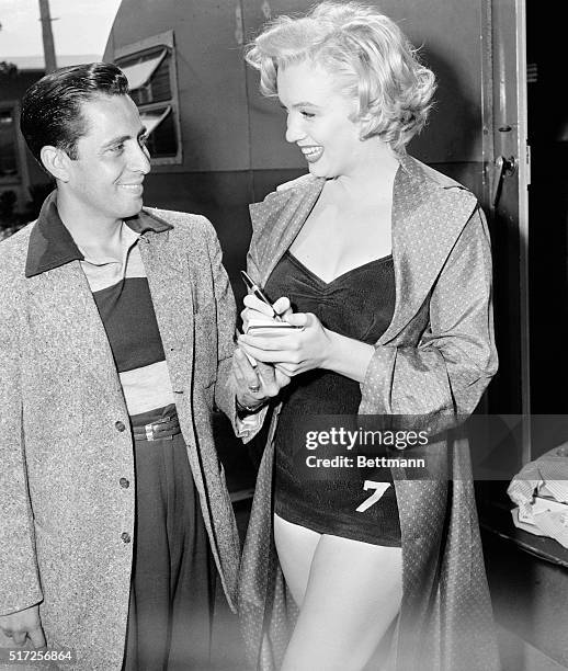 Marilyn Monroe is shown in a bathing suit, and signing an autograph for a fan.