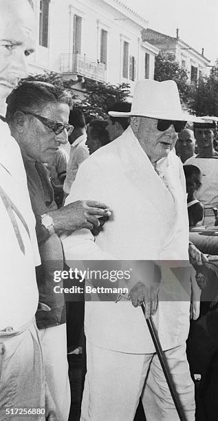 Former British Prime Minister Winston Churchill , is assisted by shipping magnate Aristotle Onassis, , as they walk to their car. Touring the Aegean...