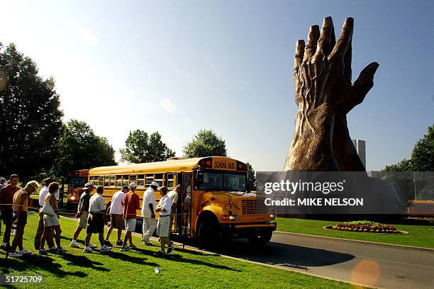 Open spectators line up to board buses next to the huge praying hands at Oral Roberts University as practice rounds at the Southern Hill Country Club...