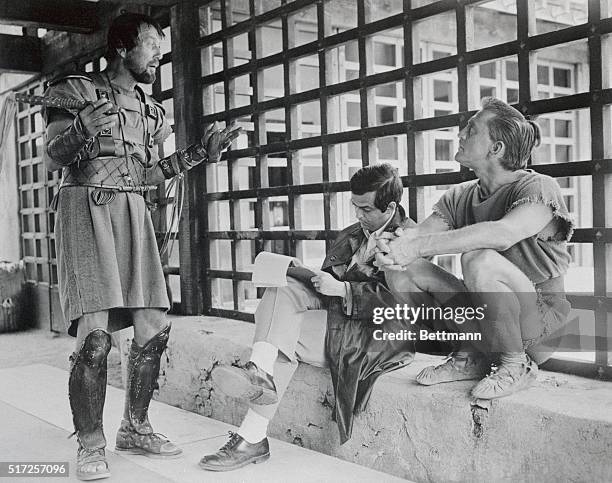 Director Stanley Kubrick makes notes on his script while Charles McGraw and Kirk Douglas discuss a forthcoming scene for the 1960 film Spartacus.