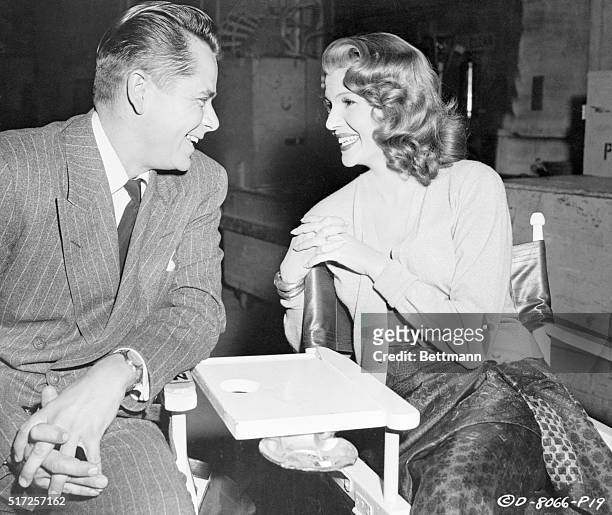 Actors Rita Hayworth and Glenn Ford chat between takes during the filming of 'Affair in Trinidad', directed by Vincent Sherman.
