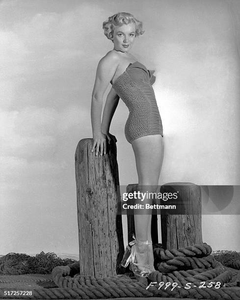 Actress Marilyn Monroe poses in her bathing suit on a pier.