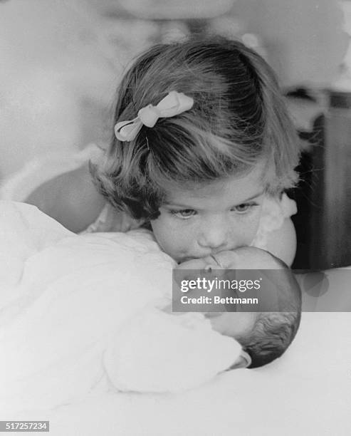 Caroline Kennedy kisses her new brother, John F. Kennedy, Jr., in this picture made during the Kennedys' pre-inaugural stay in Palm Beach, Florida....