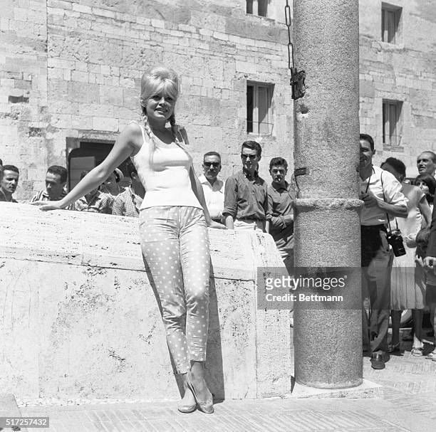 France's movie star Brigitte Bardot, wearing tight Capri-style pants, ;jeans provocatively against wall during current visit to Italy. She seems to...