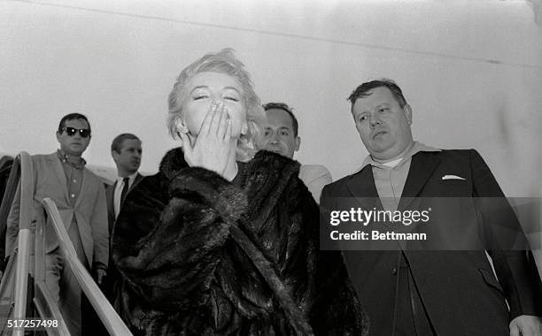 Curvaceous Marilyn Monroe arrives, sleepy-eyed but wide-awake enough to throw a kiss to her public at Idlewild Airport. The star arrived at 7:55 a.m....