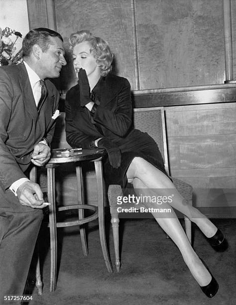 Marilyn Monroe confidentially whispers to Sir Laurence Olivier at the Savoy Hotel today during her press conference...her 3rd press conference in 3...