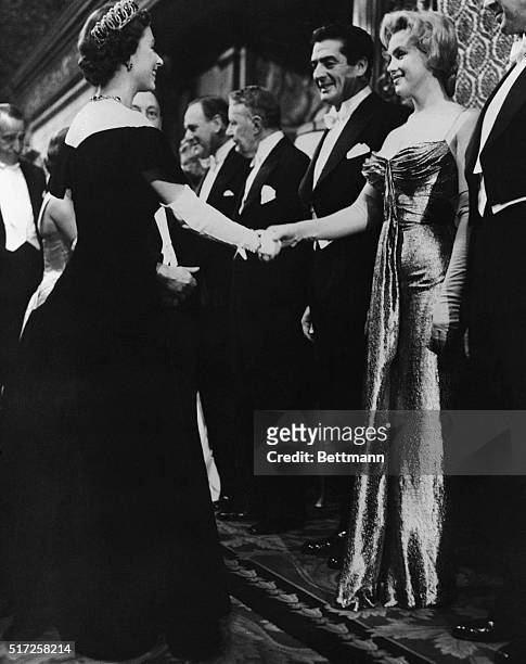 Queen Elizabeth II of England offers a gloved hand to Hollywood glamour girl Marilyn Monroe Miller during the Queen's visit with celebrities at the...