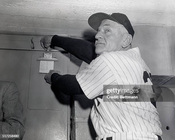 New York Yankee manager Casey Stengel posts the lineup for todays sixth World Series game in the dugout prior to the start of the battle of the Big...