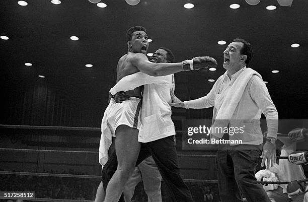 Cassius Clay is embraced by his handlers after he won the world heavyweight championship on a TKO over Sonny Liston in the 7th round.