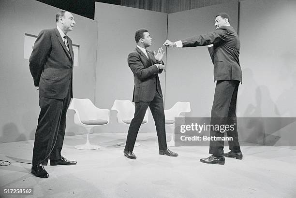 As Howard Cosell looks on, Muhammad Ali attempts to ward off a playful jab thrown by Wilt Chamberlain just before the taping of a television show....