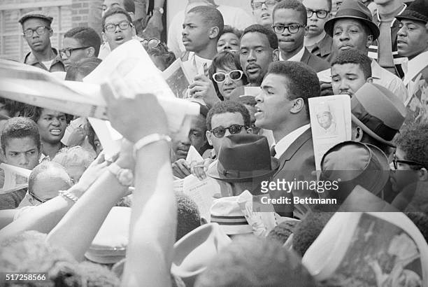 Heavyweight champion Cassius Clay is surrounded by fans seeking autographs after an appearance at the Howard University here today. Clay spoke at a...