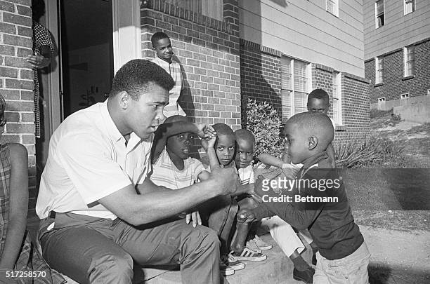 Heavyweight champion Cassius Clay playfully spars with an unidentified Negro boy after Clay learned that he has won a delay in his 4/11 draft call....