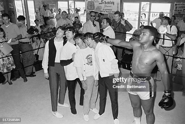 Boxer Cassius Clay later known as Muhammad Ali playfully hits The Beatles while at his training camp. From left to right: Paul McCartney, John...