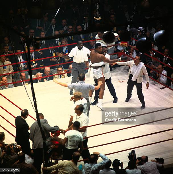 Handlers rush in to embrace the jubilant Cassias Clay after he won the heavyweight boxing title when champ Sonny Liston, seated in his corner,...