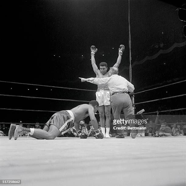 Referee John LoBianco waves champion Cassius Clay to a corner as challenger Zora Folley rises from the canvas after being knocked down in the fourth...