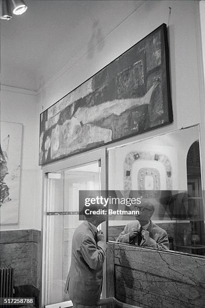 Charles Jackson adjusts his tie in the lobby of New York City's Hotel Chelsea before going out into the street. Art work by residents adorns the...