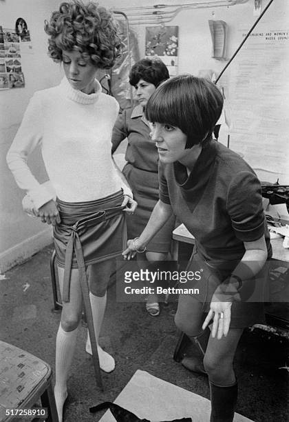 Fashion designer Mary Quant adjusts a miniskirt on a fashion model.