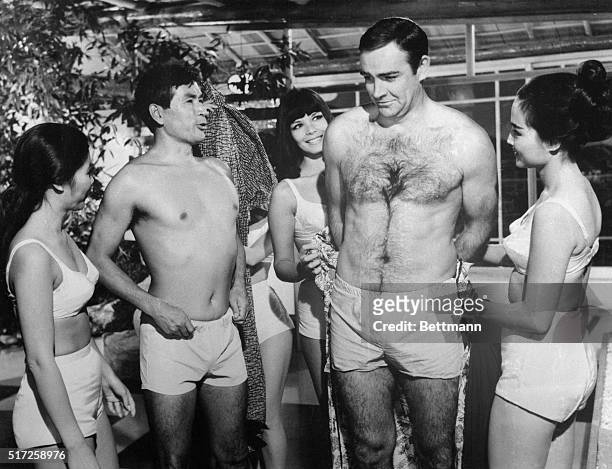 Young ladies help Sean Cannery and Tetsuro Tamba disrobe down to their shorts in a scene from the movie You Only Live Twice. Nowadays, it's not...