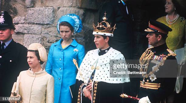 Prince Charles stands on castle steps after being invested as Prince of Wales. He is flanked by his mother, Queen Elizabeth II, and father, Prince...