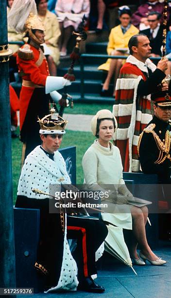 Wearing gold coronet and robe and holding sceptre of his authority, Prince Charles, newly invested Prince of Wales, sits with his mother, Queen...