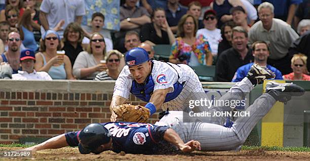 Minnesota Twins pitcher J. C. Romero slides safely into home as before the late tag of Chicago Cubs catcher Joe Girardi in the fifth inning 15 June...
