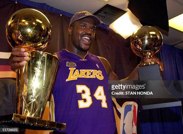 Shaquille O'Neal holds the MVP trophy and the Larry O'Brian Championship trophy after the Los Angeles Lakers won game five of the NBA Finals against...