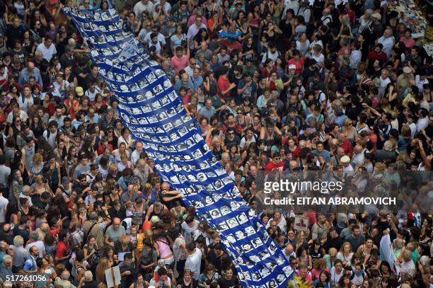 Members of the Madres and Abuelas de Plaza de Mayo Human Rights organizations and demonstrators carry a large banner with portraits of people...
