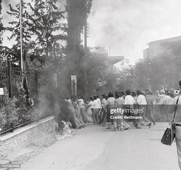 Greek Cyprist demonstrators storm the gate of the U. S. Embassy here, as police fire tear gas in efforts to keep them out. They failed, and gunmen...