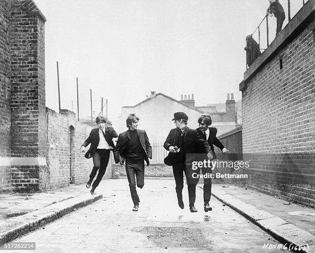 From left to right, Paul McCartney, George Harrison, John Lennon, and Ringo Starr run down an empty London street in a scene from the movie A Hard...