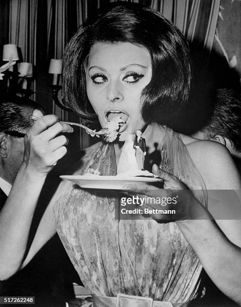 Tasty Dish. Rome: Enjoying a tasty dish, Sophia Loren candidly polishes off the last piece of cake from a saucer decorated with a miniature bride and...