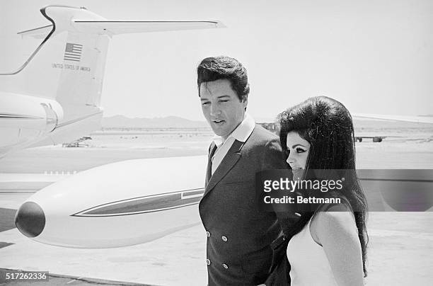 Singer Elvis Presley and his bride Priscilla Ann Beaulieu smile happily as they prepare to board a chartered jet airplane after their marriage at the...