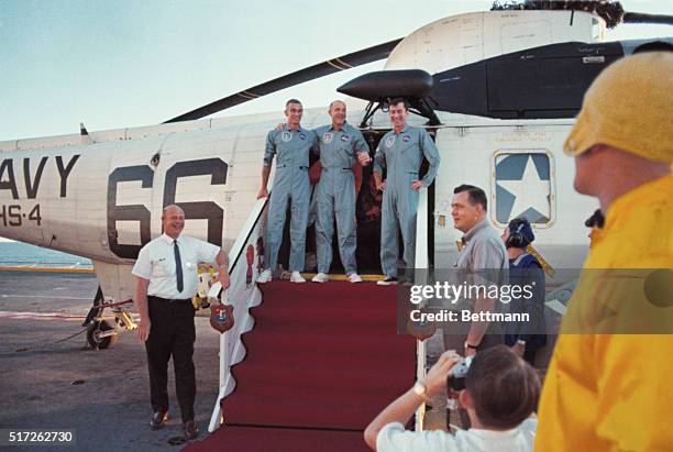 Apollo 10 astronauts : Eugene Cernan, Thomas Stafford and John Young, stand smiling in door of helicopter which landed them aboard the aircraft...