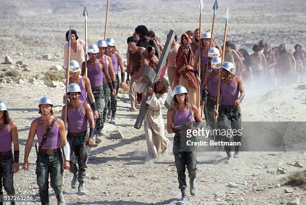 Jesus, played by Ted Neely, carries the Cross while flanked by anachronisticly clad Roman soldiers, in a scene from the 1973 motion picture Jesus...