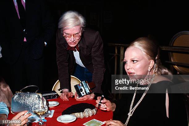 Artist Andy Warhol chats with singer Peggy Lee at the Waldorf Astoria Hotel.