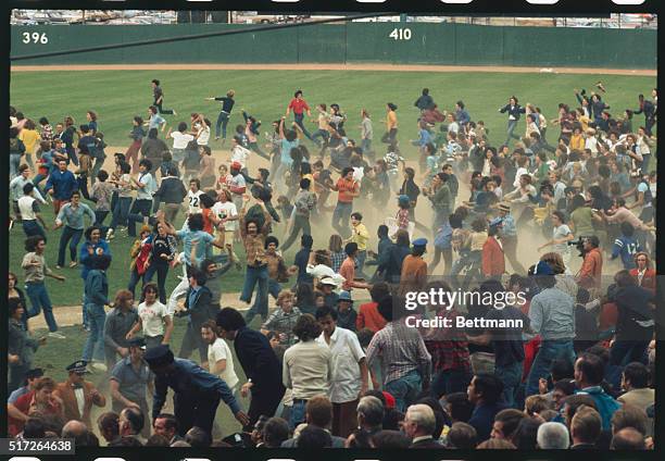 New York: Fans swarm into the field at Shea Stadium after Mets beat Reds, 7-2, to win NL pennant. Fan tries to grab red hat from head of Cincinnati's...