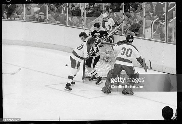 Bloomington, Minnesota: North Stars' defenseman Tom Reid pins Bruin's Andre Savard to the front of the goals preventing him from reaching the puck...