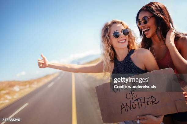 two hipster girls hitchhiking together - hitchhiking 個照片及圖片檔