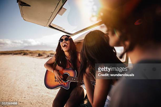 hipster multi-ethnische gruppe spielt gitarre am strand - us girls on the beach stock-fotos und bilder