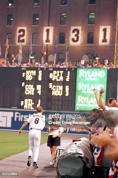 Cal Ripken Jr. #8 of the Baltimore Orioles high-fives fans along side the warning track as he celebrates breaking Lou Gehrig's record for consecutive...