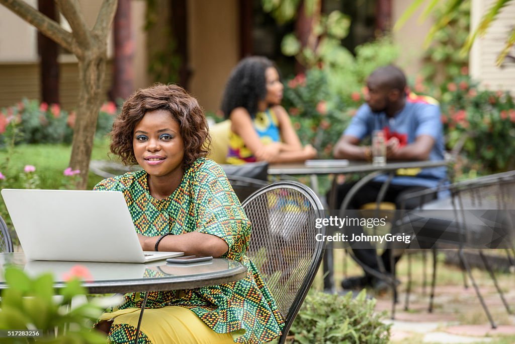 Jóvenes Africano mujer mirando a cámara utilizando una computadora portátil