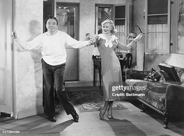 Still sitting pretty...Ginger Rogers and Jack Haley kick up their heels in this scene in Sitting Pretty, a film released by Paramount Pictures in...