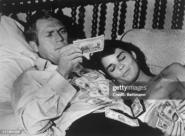 Steve McQueen and Ali McGraw in a scene from the 1972 movie "The Getaway." McGraw and McQueen are lying in bed with a pile of money.