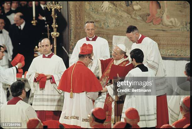 Vatican City: Pope Paul VI placing red "beretta" hat on head of Timothy Cardinal Manning, Archbishop of Los Angeles during consistory ceremony.