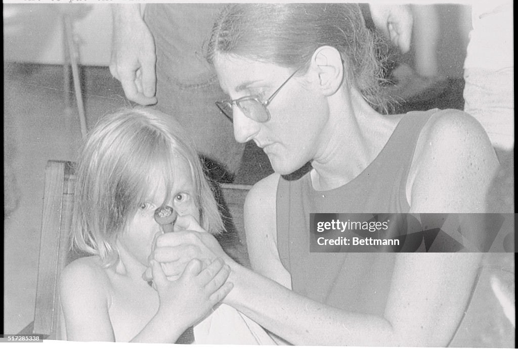 Woman Helping Young Child Smoke Pipe