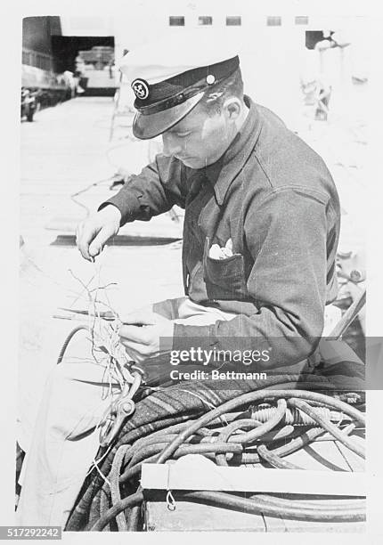 Candid camera goes down to the ships and sees Herman Wegge, second mate of Harold S. Vanderbilt's Ranger, doing a splicing job-one of the many tasks...