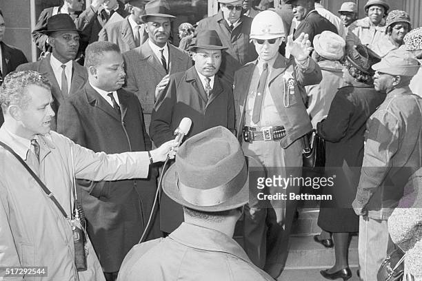 Dr Martin Luther King Jr listens as Dallas County deputy sheriff LC Crocker explains how to line up marchers registering to vote in Selma, Alabama.