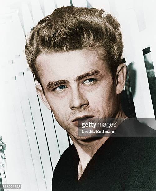 Actor James Dean leaning against a picket fence.