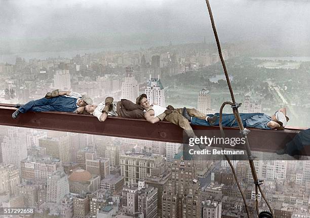 Four construction workers take a nap, balanced on a steel girder hung 800 feet over Manhattan, during the construction of the RCA Building. Man on...