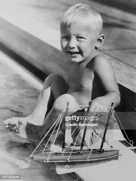 Young Skipper. Buzz Aldrin., of Montclair N.J., tries the water for temperature before setting sail at Miami Beach, Fla., where his parents are...