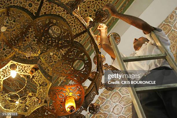 Egyptian workers clean the glass diffusers of a chandelier in the King Faisal Mosque close to the international airport in Cairo 11 November 2004,...